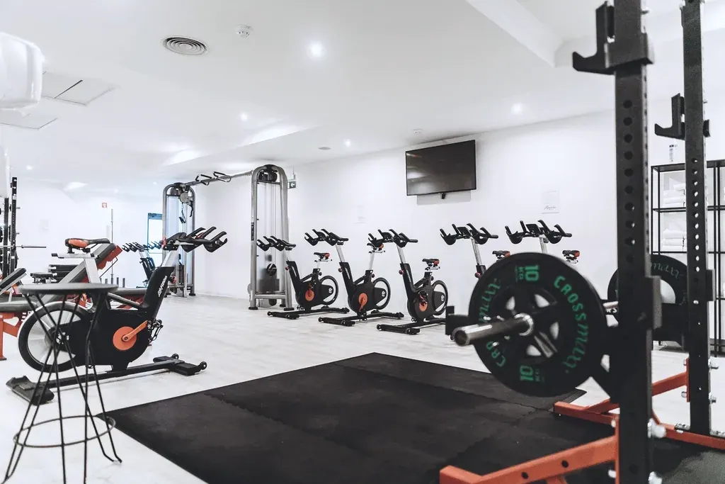 A bright gym with spin bikes, a squat rack and rubber flooring