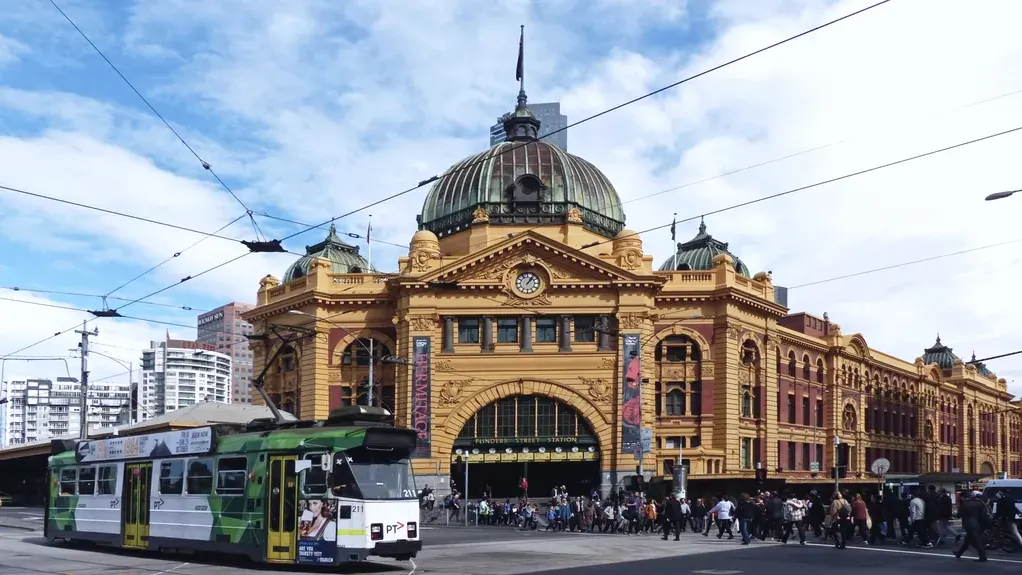 A tram stopped at a platform beside a station building